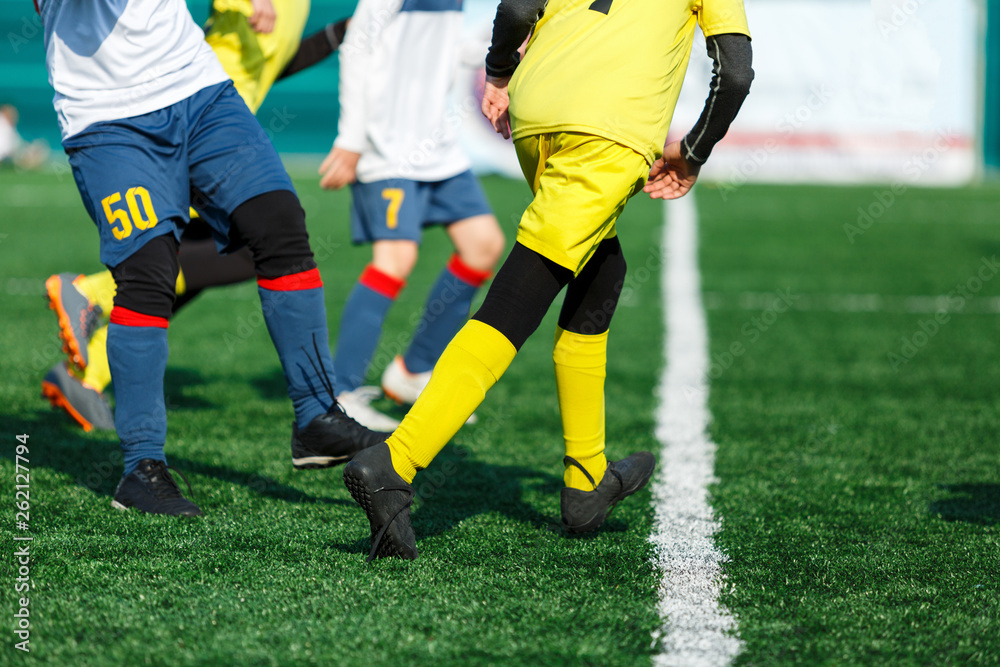Boys in yellow white sportswear running on soccer field. Young footballers dribble and kick football ball in game. Training, active lifestyle, sport, children activity concept Boys in yellow white sportswear running on soccer field. Young footballers dribble and kick football ball in game. Training, active lifestyle, sport, children activity concept