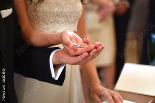 Hands of the groom and bride hold the wedding rings in front of the altar