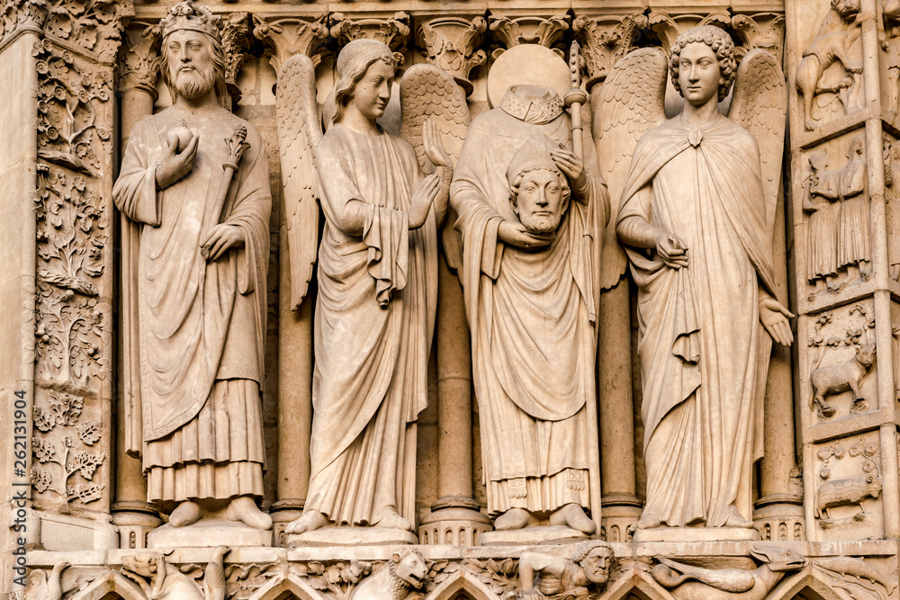 The four large statues of the left-hand side of the portal of the Virgin represent an unidentified king and Saint Denis decapitated