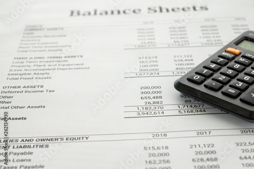 Balance sheet report with calculator accounting report and financial statement on desk , document is mock-up. Accounting business concept. © Choo