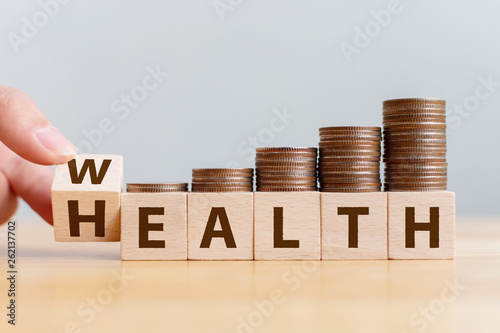 Hand flip wooden cube with word wealth to health with coins stack step up growing growth value. Investment in life insurance and healthcare concept photo