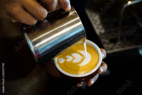 Close up barista hands pouring froth milk in espresso coffee cup for making latte art