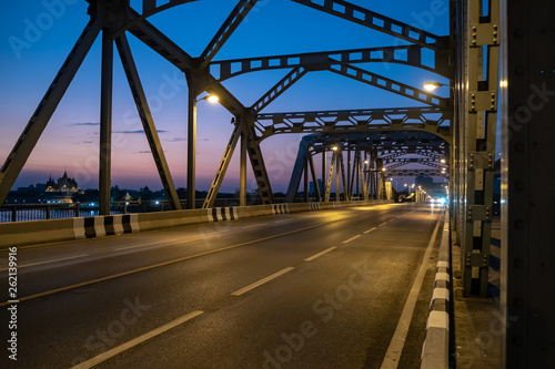 Empty old steel structure bridge over the river on clear twilight sky background