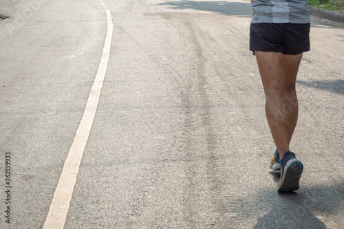 The bottom of the runner who wearing grey and white sport shirt and black sport shorts are jogging in the city park in the morning with copy space