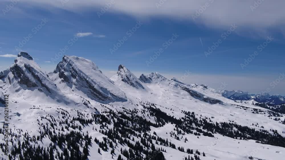 Fly over trees and you have a beautiful view to the mountains. The sky is blue and the landscape snowy. Fly over trees and you have a beautiful view to the mountains. The sky is blue and the landscape snowy.