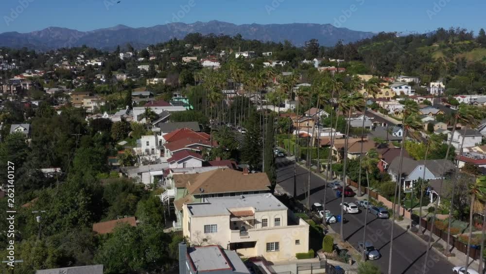 Drone flys over iconic Los Angeles palm tree lined street with the city skyline in the background. Drone flys over iconic Los Angeles palm tree lined street with the city skyline in the background.