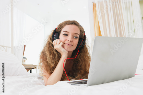 Girl sleeping on the bed, listening to music on the computer.