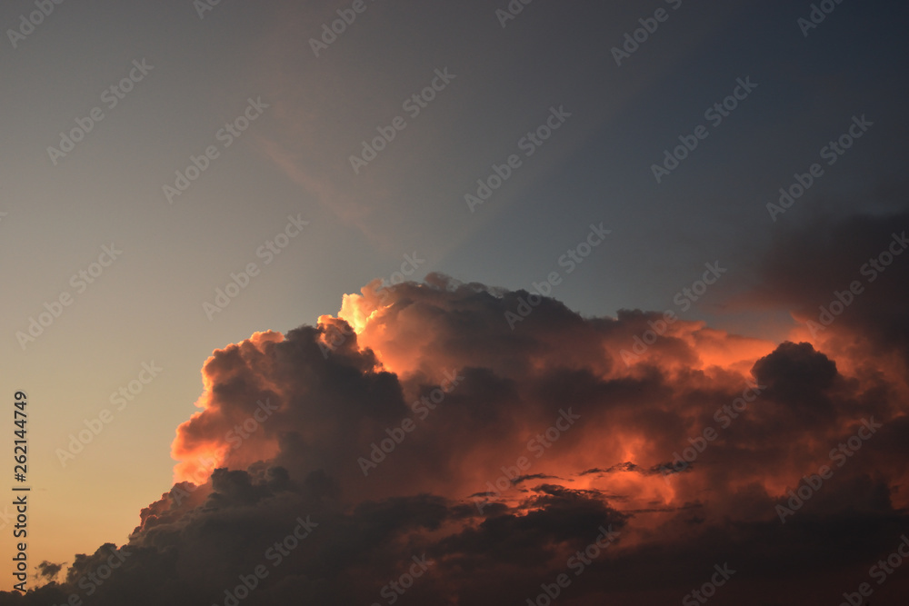 Cumulonimbus cloud formations on tropical sky with horizon is turning yellow at sunset , Nimbus moving , Purple and orange color clouds hunk at night , Thailand