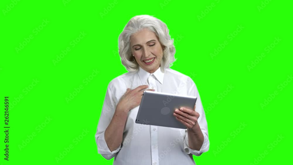 Senior woman with tablet pc having video call. Green Chroma Key background. Modern technology, communication concept. Senior woman with tablet pc having video call. Green Chroma Key background. Modern technology, communication concept.