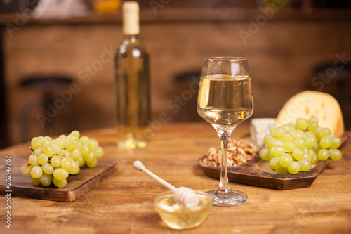 Various cheeses with a bottle and glass of wine over yellow background