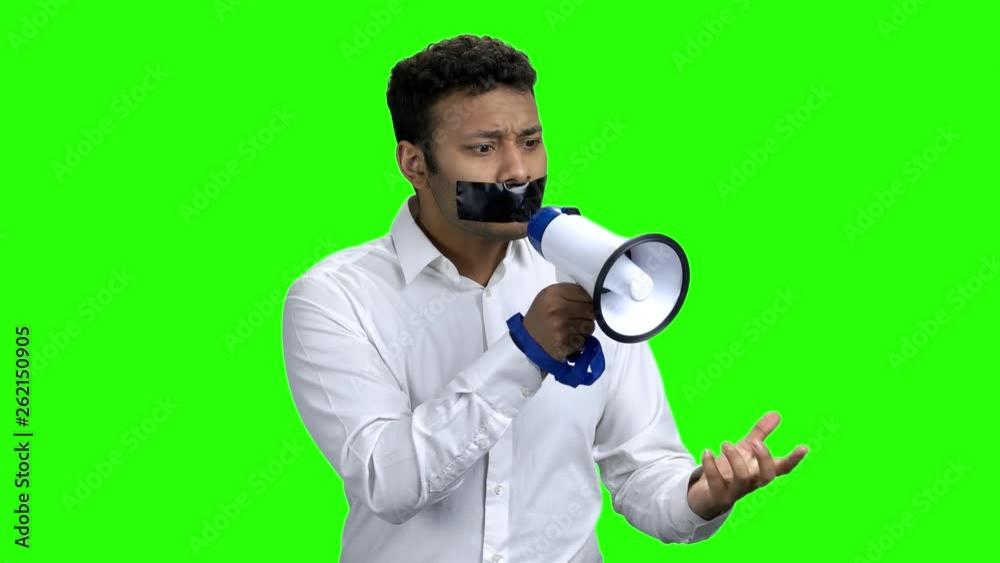 Man with taped mouth trying to speak. Young businessman with black tape over mouth holding megaphone and gesturing with hand. Chroma Key background. Man with taped mouth trying to speak. Young businessman with black tape over mouth holding megaphone and gesturing with hand. Chroma Key background.