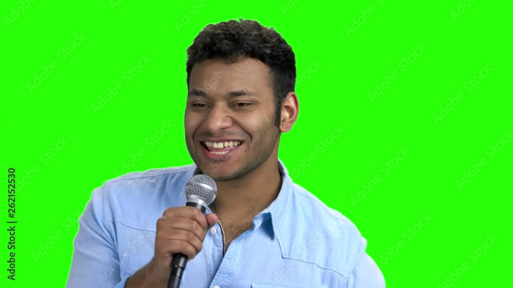 Energetic entertainer talking into microphone on green screen. Enthusiastic good-looking speaker talking in microphone. Alpha Channel background.