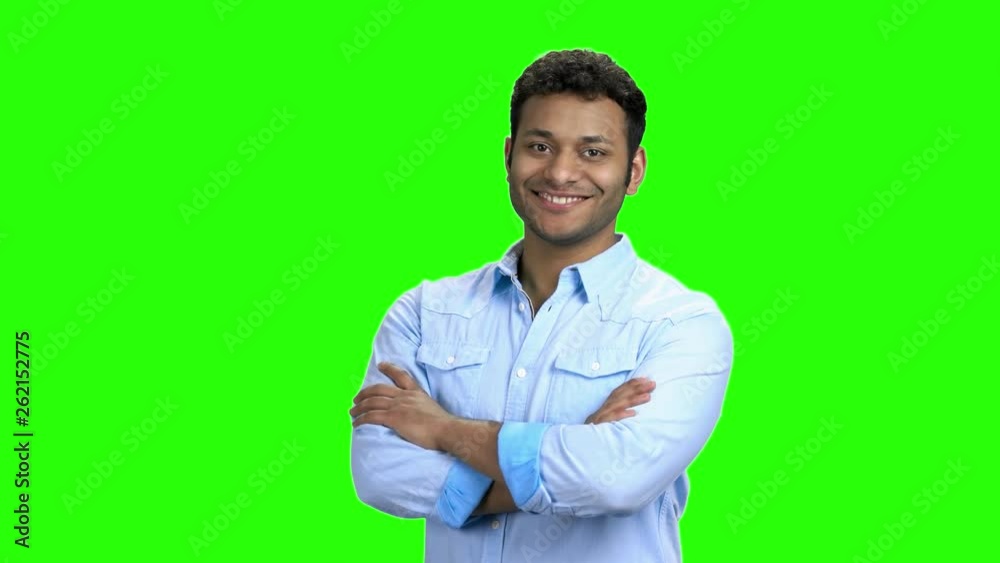 Young man crossed arms on green screen. Handsome cheerful guy posing with folded arms on Alpha Channel background.