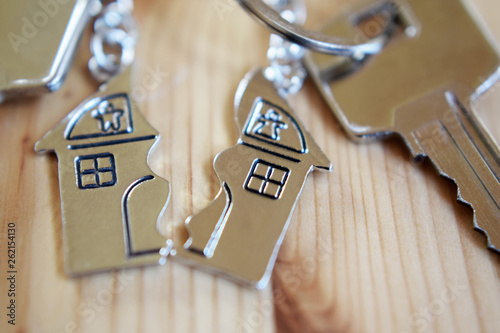Wallpaper Mural Splitted or broken  pendant of key ring in shape of house divided in two parts on wooden background, closeup view. Dividing house when divorce, division of property and real estate. Torontodigital.ca