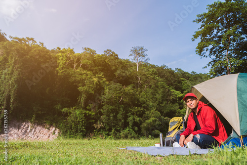 Young asian tourist backpacker sitting in a tent camping in Forest. Image of camping,travel,lifestyle or recreation concept.