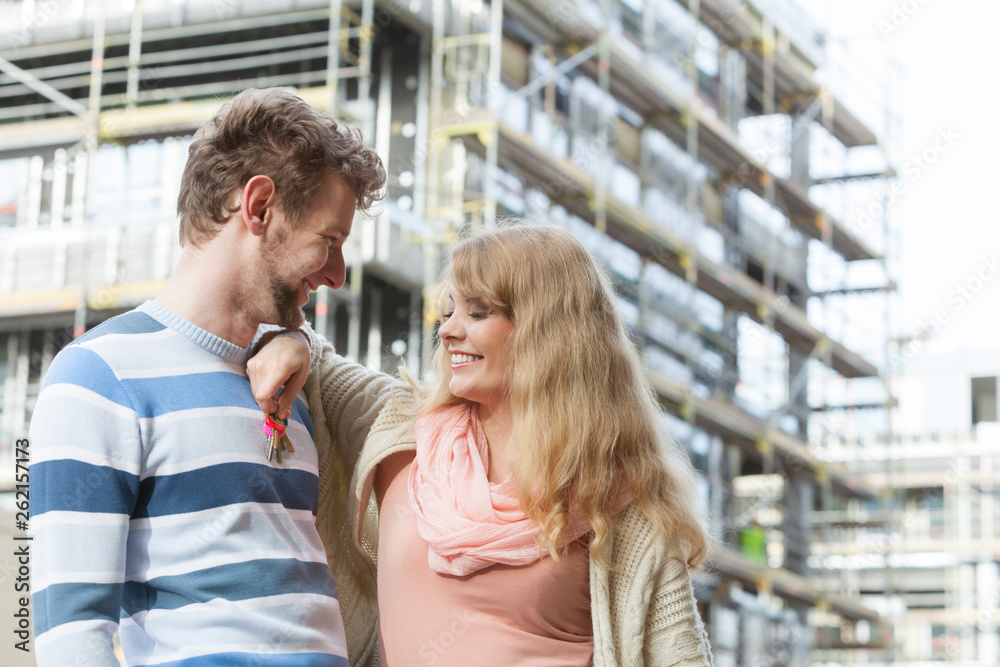 Couple with keys on front of new modern house Couple with keys on front of new modern house