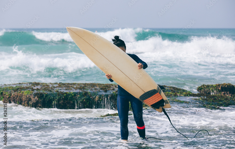 Naklejka premium Woman surfer with surfboard going to surf