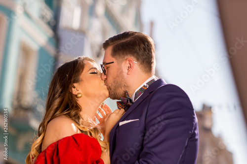 Beautiful couple posing outdoor, happy woman in red dress and handsome man posing in blue suit © hreniuca