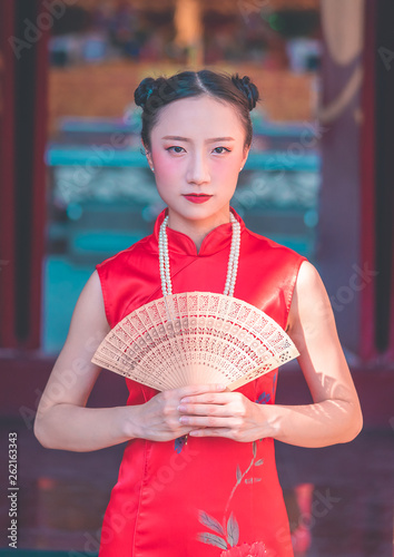 front view of a chinese woman with wooden fan in temple