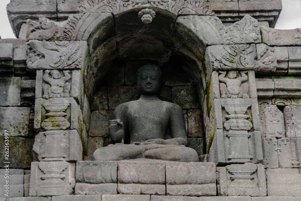 A statue of seated Buddha in a niche of the Borobudur Temple