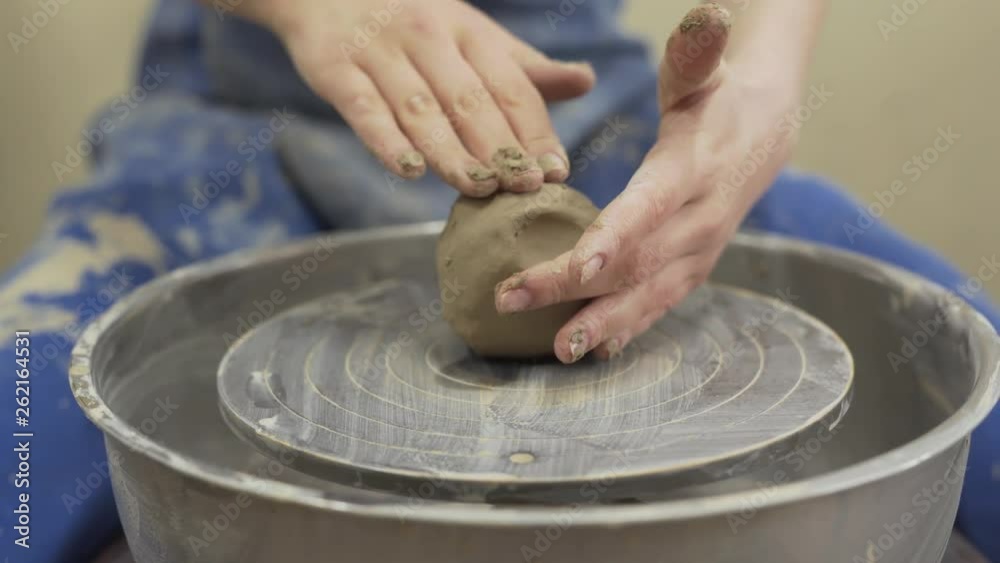 A close up video of some clay on the spinning wheel. The skilful female master / potter in apron sits on the chair and moulds / shapes clay. The background is blurred. A close up video of some clay on the spinning wheel. The skilful female master / potter in apron sits on the chair and moulds / shapes clay. The background is blurred.