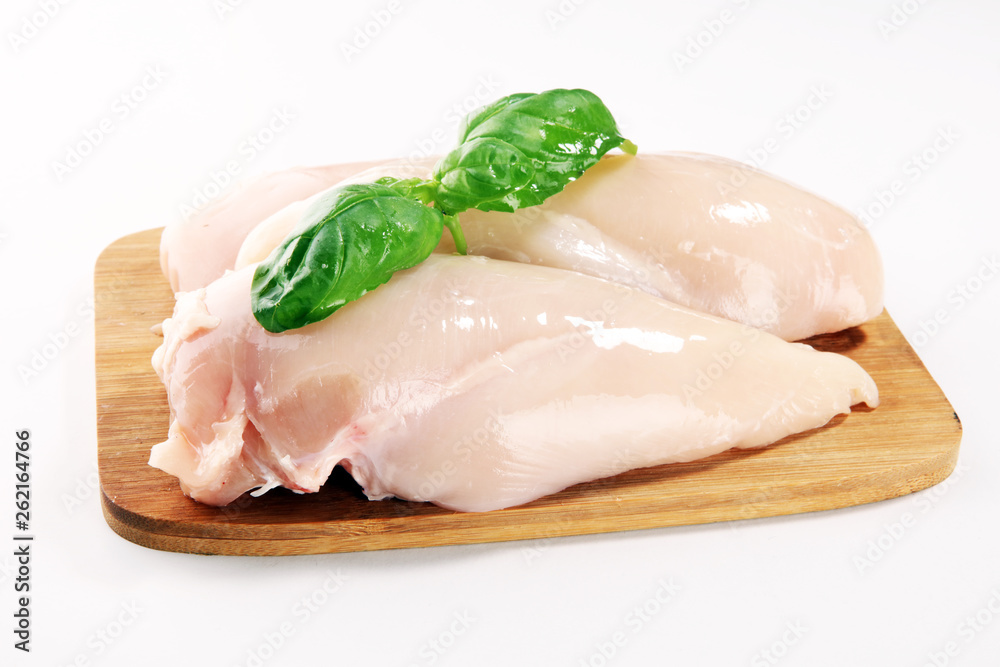 Raw chicken breasts and spices on wooden cutting board, close up Raw chicken breasts and spices on wooden cutting board, close up