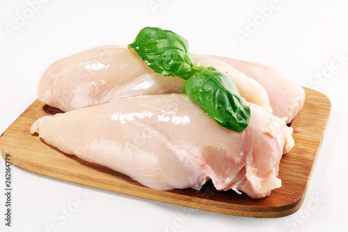 Raw chicken breasts and spices on wooden cutting board, close up
