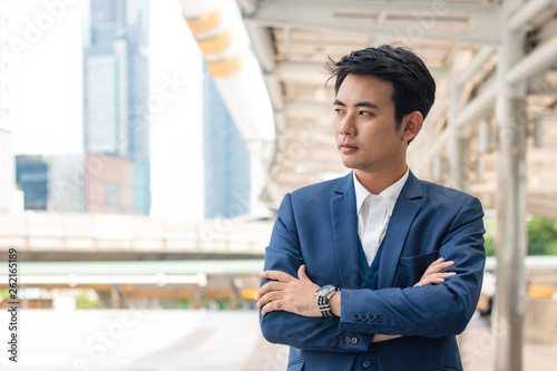 Handsome young businessman holding arms folded.