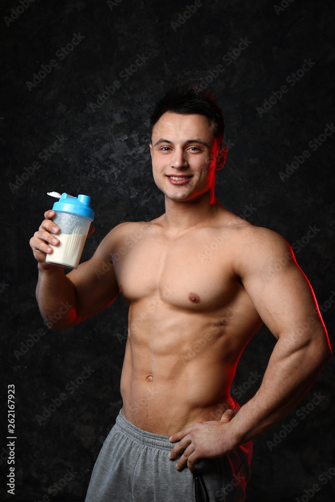 Sporty man with protein shake on dark background Sporty man with protein shake on dark background