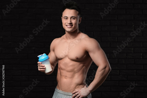 Sporty man with protein shake on dark background