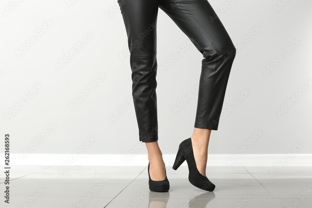 Stylish young woman in high heels near light wall Stylish young woman in high heels near light wall
