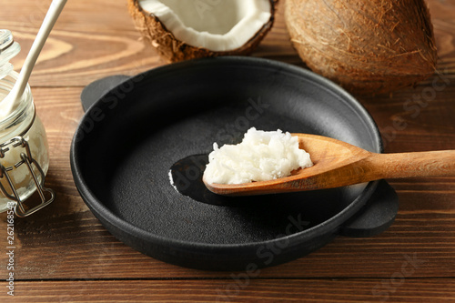Frying pan with coconut oil on wooden table