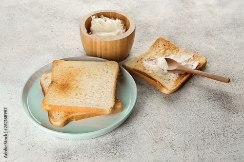 Tasty toasted bread with coconut oil on light background