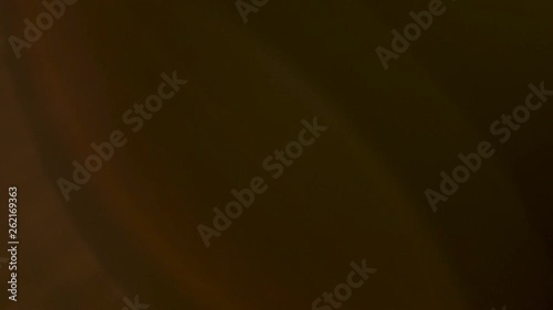 Warm rays of light for overlay or transition purposes. Optical lens flare effect over a dark background.