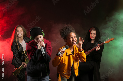 Band of teenage musicians on dark background