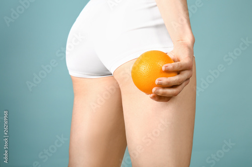 Sporty woman with orange on color background, closeup