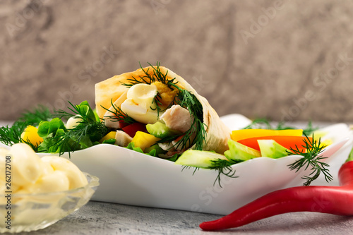 Burrito with hot pepper and white sauce. Mexican traditional food. Roll with meat and fresh vegetables.