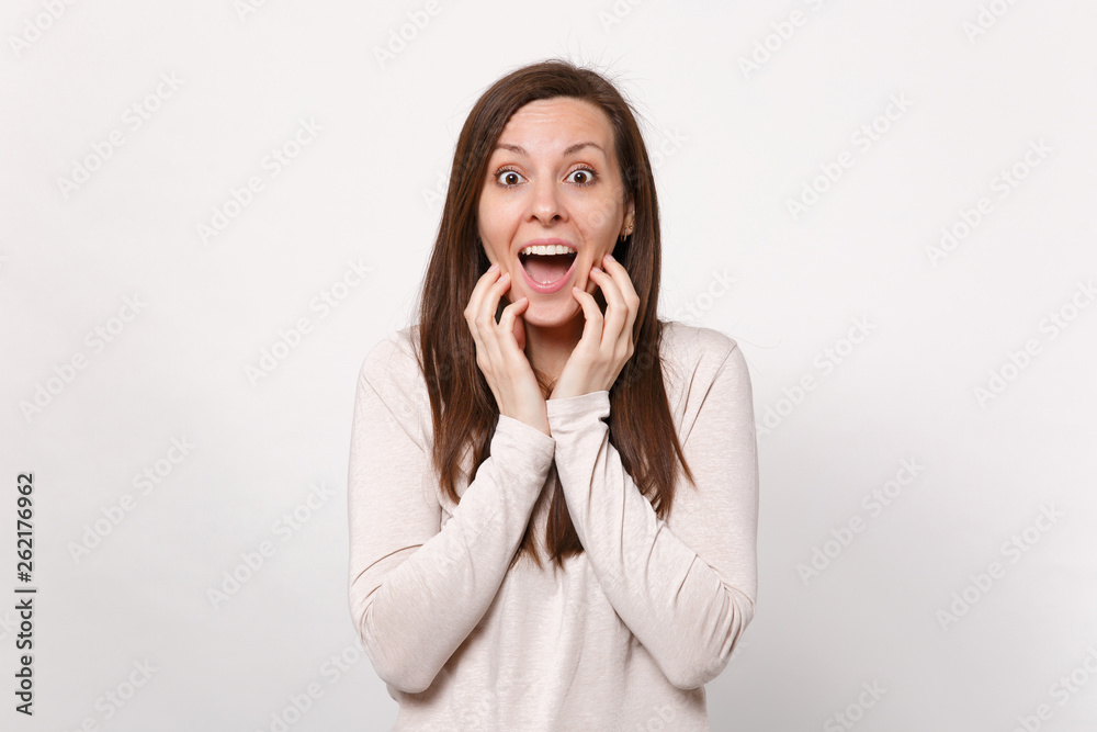 Portrait of excited young woman in light clothes keeping mouth wide open putting hands on cheeks isolated on white background in studio. People sincere emotions, lifestyle concept. Mock up copy space. Portrait of excited young woman in light clothes keeping mouth wide open putting hands on cheeks isolated on white background in studio. People sincere emotions, lifestyle concept. Mock up copy space.