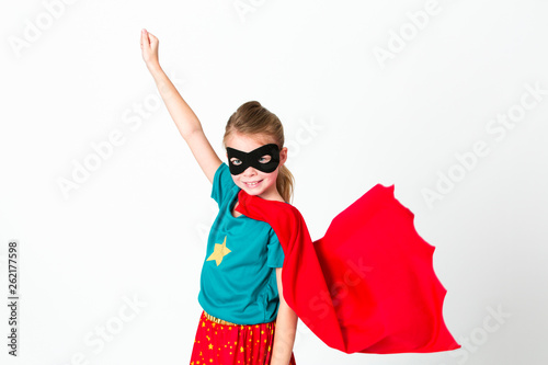 Obraz na plátne blond supergirl with black mask and red cape posing in front of white background