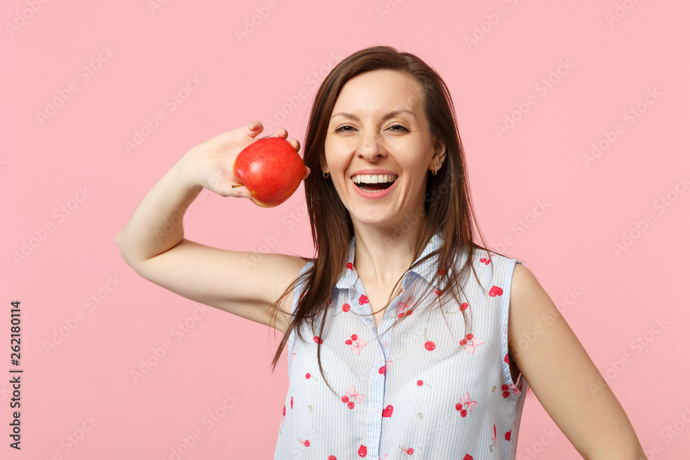 Laughing young woman in summer clothes holding fresh ripe red apple fruit isolated on pink pastel wall background, studio portrait. People vivid lifestyle, relax vacation concept. Mock up copy space. Laughing young woman in summer clothes holding fresh ripe red apple fruit isolated on pink pastel wall background, studio portrait. People vivid lifestyle, relax vacation concept. Mock up copy space.