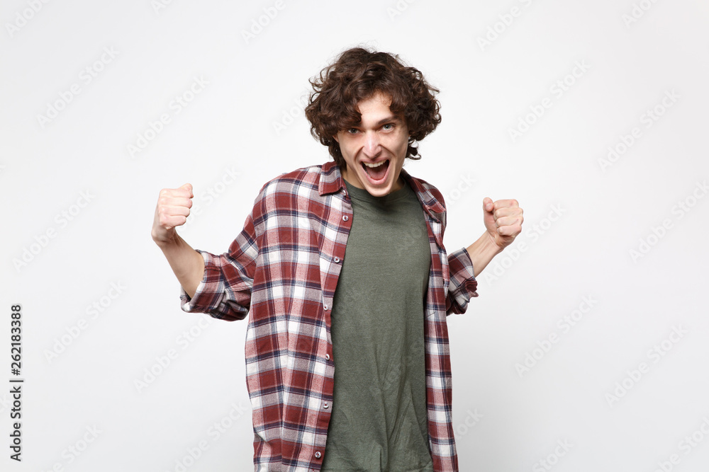 Portrait of overjoyed screaming young man in casual clothes clenching fists like winner isolated on white wall background in studio. People sincere emotions, lifestyle concept. Mock up copy space.