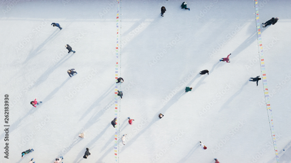 Aerial view of a drone on an open ice rink with people on a winter sunny day.