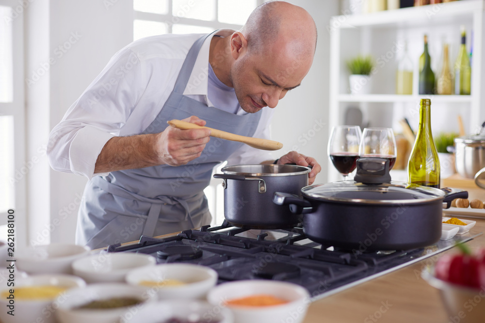 Handsome man is cooking on kitchen and smiling Handsome man is cooking on kitchen and smiling