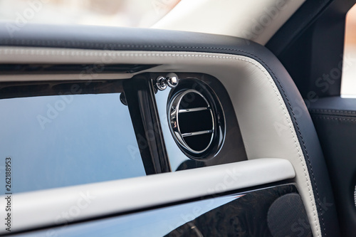 A close-up view of a part of the interior of a modern luxury car with a view of the ventilation deflector of the stove for heating and cooling the passenger compartment with black trim elements