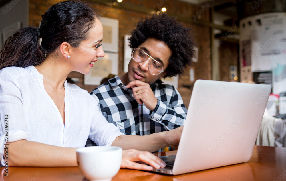 Multiethnic people meeting at cafe, advisor showing offer to client on laptop Multiethnic people meeting at cafe, advisor showing offer to client on laptop