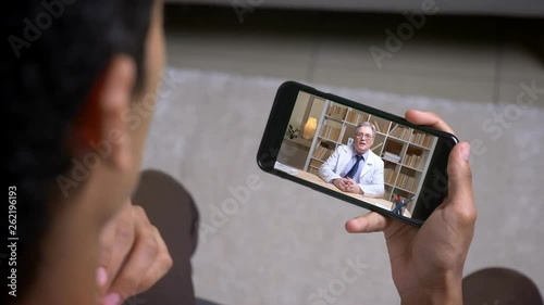 Doctor talks to patient during telehealth visit on smartphone photo