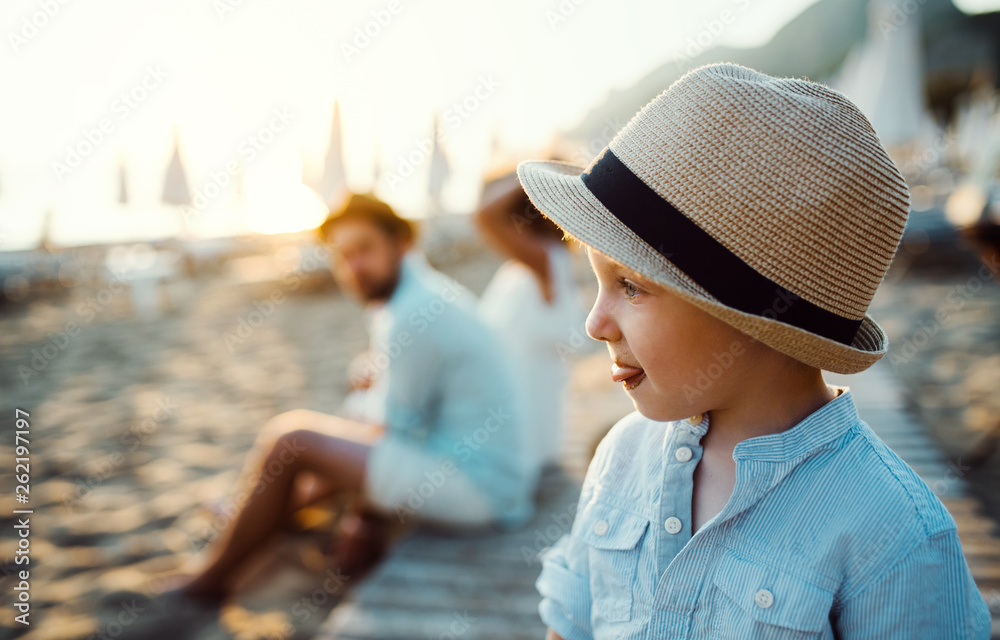 A small toddler boy with a hat on beach on summer holiday. Copy space.
