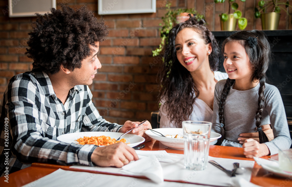 Happy african american family eating lunch together at restaurant and having fun Happy african american family eating lunch together at restaurant and having fun