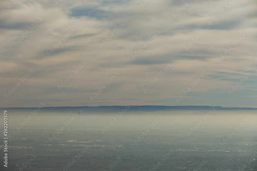 Landschaft Rheinebene mit Windrädern unter einer Nebeldecke und Wolkendecke