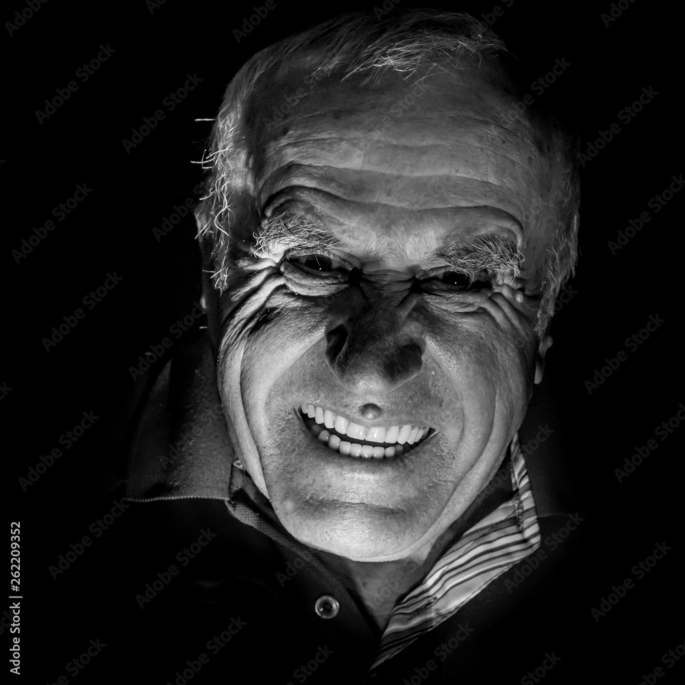 Portrait of old caucasian man who scares watcher. Fear and scare concept. Black and white shot, low-key lighting. Isolated on black. Portrait of old caucasian man who scares watcher. Fear and scare concept. Black and white shot, low-key lighting. Isolated on black.